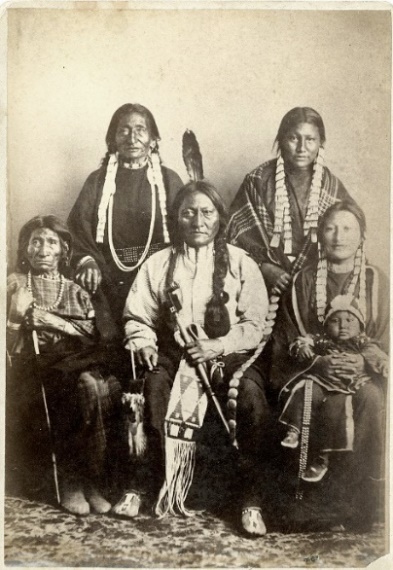 G:\pix\Sitting Bull and family 1881 at Ft Randall rear L–R Good Feather Woman (sister), Walks Looking (daughter) front L–R Her Holy Door (mother), Sitting Bull, Many Horses (daughter) with her son, Courting a Woman.jpg