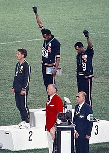 https://upload.wikimedia.org/wikipedia/commons/thumb/3/3e/John_Carlos%2C_Tommie_Smith%2C_Peter_Norman_1968cr.jpg/220px-John_Carlos%2C_Tommie_Smith%2C_Peter_Norman_1968cr.jpg