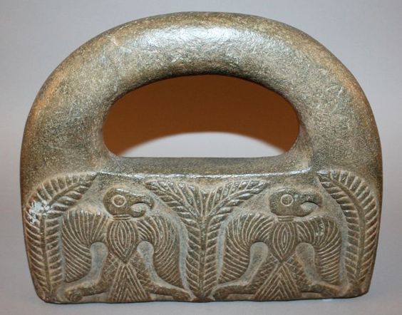 A PERSIAN JIROFT STONE WEIGHT, possibly early, carved in relief to one side with two stylised confronting snakes, and to the reverse side with two winged hawks, 10.1in wide & 8.5in high.