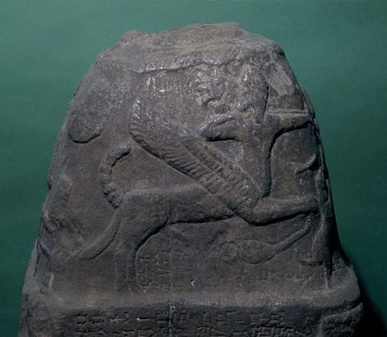 Stone kudurru inscribed with details of a royal gift of farmland; columns of writing presented as the walls of a fortress; upper part of stone carved with divine symbols; figure with twining legs, 2 headed, 2 tailed centaur (winged), precursor of Sagittarius, drawing a bow.