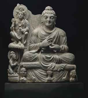 A gray schist relief of Buddha with Avalokiteshvara Gandhara, 2nd/3rd century Buddha seated on a cushion over a throne with hands in dharmachakramudra, Avalokiteshvara seated on a throne and holding lotuses to his upper right, a kneeling acolyte below 15 1/8 in. (38.4 cm.) high