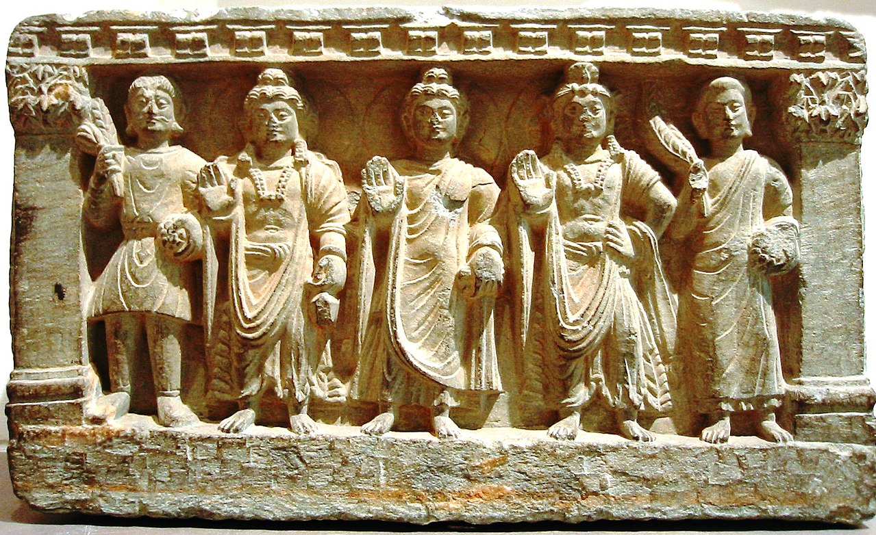 An early Mahayana Buddhist triad. From left to right, a Kushan devotee, the Bodhisattva Maitreya, the Buddha, the Bodhisattva Avalokitesvara, and a Buddhist monk. from the 2nd-3rd century AD