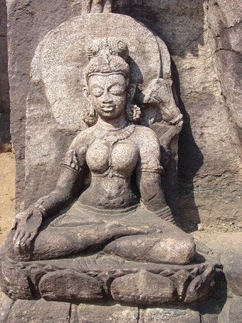 Seated Tara. Detail from a Bodhisattva statue. West of inner entrance of Monastery 1, Ratnagiri. This lovely Tara is a companion to the headless statue of Avalokiteshvara on site. Tara extends her right hand in varada mudra, while a lotus flower curls above her left shoulder.