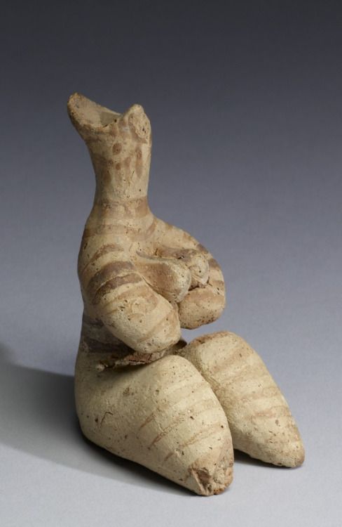 "Tel Halaf" - Fertility Figurine - Syria - 5000-4000 BC - Terracotta w/traces of pigment -  As early as the 7th millennium BC, cultures in the Near East began to create organized settlements with well-developed religious and funerary practices. Â The Halaf culture of Anatolia (central Turkey) and northern Syria arose around 5000 BC and produced remarkable female figurines with distinctive fertility attributes. This statuette is seated wlegs extended, her arms cradling her protruding breasts...