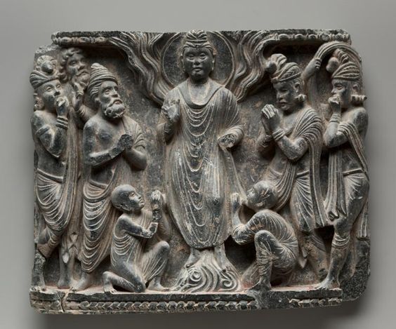 The Great Miracle at Shravasti.(1st century-320). Pakistan, Gandhara.After the Buddha reached enlightenment, he spent the remainder of his life traveling around northeastern India, giving teachings and performing miracles in order to convert followers and establish the Buddhist community. One of his most famous miracles is when he levitated and caused fire to leap from his shoulders and water to flow from his feet. The figures of two monks kneel in worship.